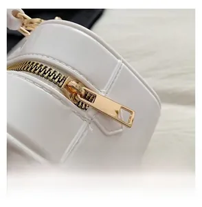 Détail du zip métallique doré lisse et de la matière en cuir verni blanc brillant