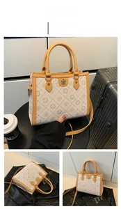 Détail d'un sac cabas beige avec imprimés lettres, logo doré et anses marron
