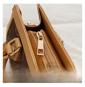 Detailed macro view of the smooth golden zipper and vintage monogram texture on the tote bag