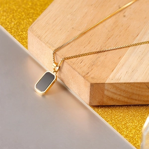 Makroaufnahme der goldenen Box-Kette mit minimalistischem schwarzem Rechteckanhänger