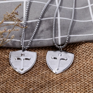 Dettaglio del ciondolo a scudo argento con croce a rilievo e scritte religiose su catenina