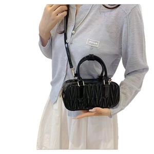 Sac Boston en cuir verni noir matelassé avec détails dorés et bandoulière réglable
