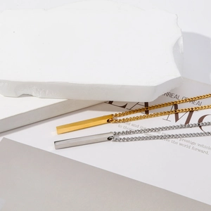 Vue détaillée des colliers pendentifs cylindriques en or et argent sur décor en pierre