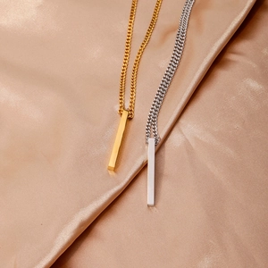 Gros plan de colliers pendentifs barres en or et argent sur tissu satiné champagne