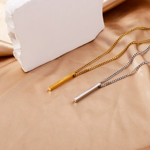 Gros plan de pendentifs barres en or et argent sur tissu en soie et bloc de pierre