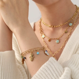 Goldenes Hamsa Evil Eye Armband und Set mit mehrlagiger Kette auf weißem Strick