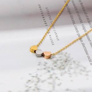 Détail de pendentifs cœur tricolores en or, argent et or rose sur une chaîne élégante