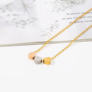 Collier minimaliste en acier titane avec trois pendentifs coeur en or argent et or rose