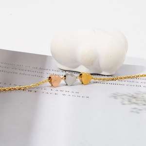 Collier en acier titane avec trois cœurs gravés MAMA sur fond de pierre blanche élégante