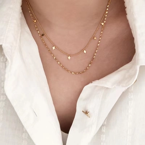 Collier doré double épaisseur avec pendentifs losange et chaîne torsadée sur chemise