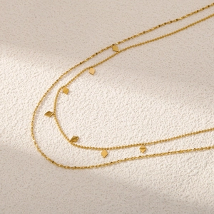 Détail du collier doré double rangée avec pendentifs losanges et chaîne à billes fine