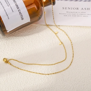 Élégant collier double épaisseur doré avec pendentifs losanges et chaîne à billes