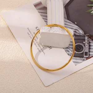 Bracelet jonc minimaliste en acier titane doré poli présenté sur un socle en marbre blanc