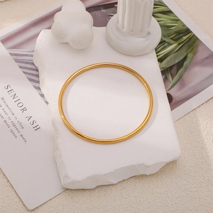 Détail d'un bracelet jonc doré poli sur une pierre blanche avec une esthétique de luxe