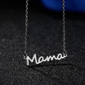 Dettaglio del ciondolo Mama in argento con finitura metallica lucida su sfondo scuro