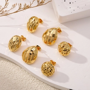 Vue détaillée de trois paires de boucles d'oreilles dorées sur une surface en marbre blanc