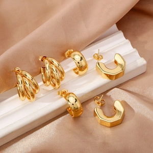 Three-piece set of elegant irregular geometric gold earrings on a white stand