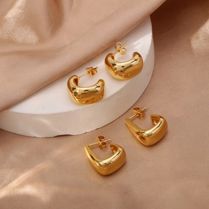 Irregular geometric chunky gold hoop earrings set on white pedestal with satin fabric