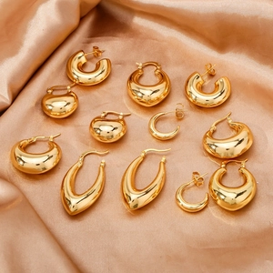 Detailed view of various polished gold irregular and teardrop earrings on silk background