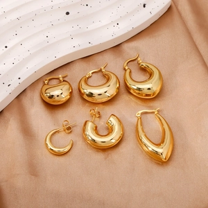 Polished gold geometric earring set featuring droplet and hoop designs on silk background