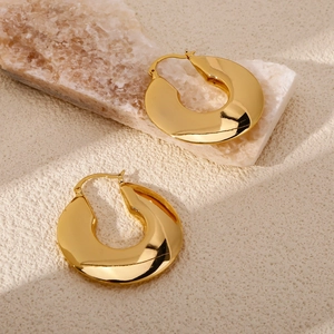 Polished chunky gold hoop earrings with flat mirror finish on stone background