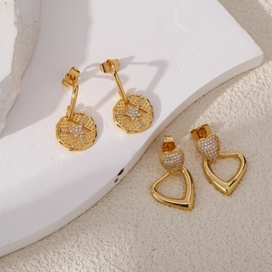Golden heart and star stud earrings with sparkling zircon stones on a white podium