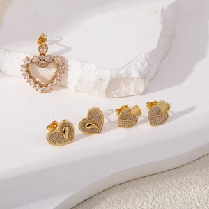 Golden heart planet earrings set with sparkling zircons on white stone pedestal