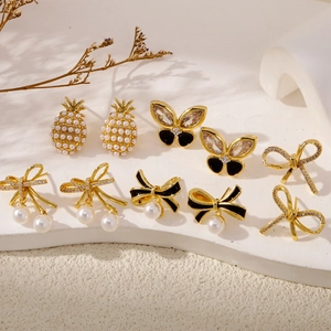 Elegant gold butterfly earrings with pearls and zircons on a white display stand