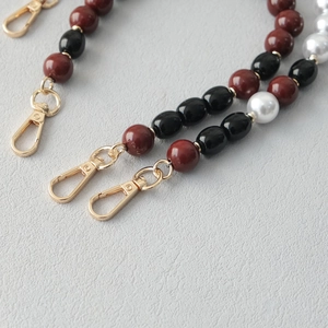 Detailed close-up of acrylic beads and faux pearls with a golden lobster clasp accessory
