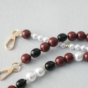 Detailed close-up of acrylic bead chain with brown, white, and black beads and gold clasps