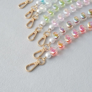 Detail of colorful acrylic heart beads and round pearls with gold lobster clasps for bags