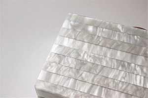 Macro shot of striped pearlescent acrylic material on a luxury evening clutch bag