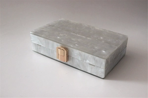 Detail view of pearlescent acrylic evening clutch with marble patterns and gold metal clasp