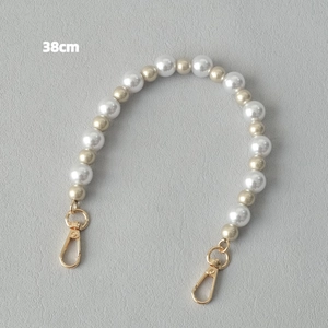 Détail d'une chaîne de sac en perles acryliques de 38cm avec perles dorées champagne