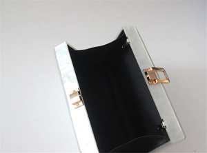 Detailed interior view of white marble acrylic clutch bag with golden metal latch