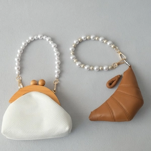 Détail du sac blanc à texture serpent et du sac croissant brun avec anses en perles