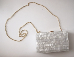 Close-up of mother of pearl striped acrylic evening bag with a golden chain strap