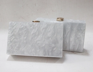 Detail view of marble pattern acrylic clutch with gold metal clasp for evening parties