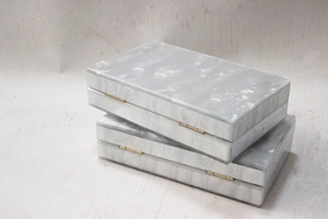 Detail view of the pearl marble acrylic clutch with gold metal hinge and sleek finish