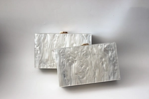 Detail view of pearlized acrylic clutch bags with marble texture and gold metal clasps