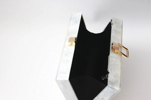 Detailed view of white marble acrylic clutch box with black lining and gold hardware
