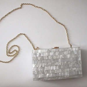 Elegant pearlescent acrylic clutch with gold chain strap and striped marble texture