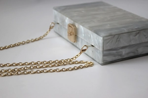 Macro shot of grey marble acrylic clutch with gold square clasp and delicate chain