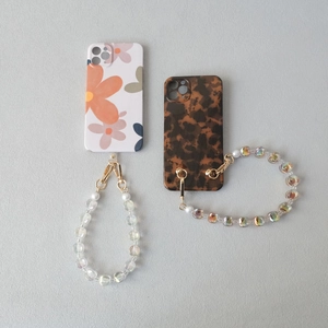 Detail of colorful acrylic bead strap on stylish floral and tortoiseshell phone cases