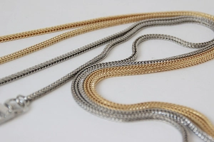 Detailed macro view of 3mm metallic gold and silver flat snake chains for bags