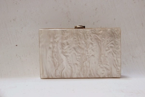 Detail view of pearlescent marble acrylic evening clutch bag with gold clasp closure