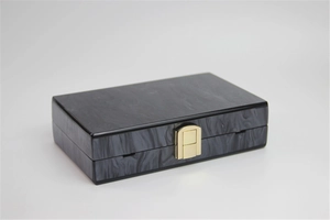 Detail of elegant black acrylic clutch bag with smoke marble texture and gold metal clasp