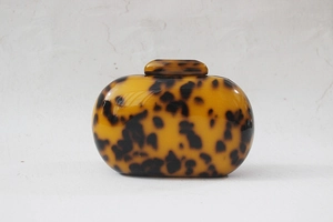 Macro detail of round leopard print acrylic clutch bag with vintage amber resin texture