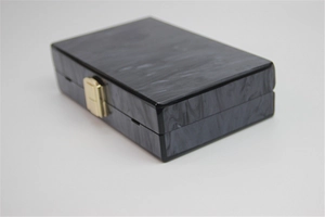Detail view of rectangular black marble acrylic evening clutch bag with gold clasp