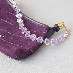 Detail of deep purple suede handbag featuring iridescent acrylic beads and pearl chain